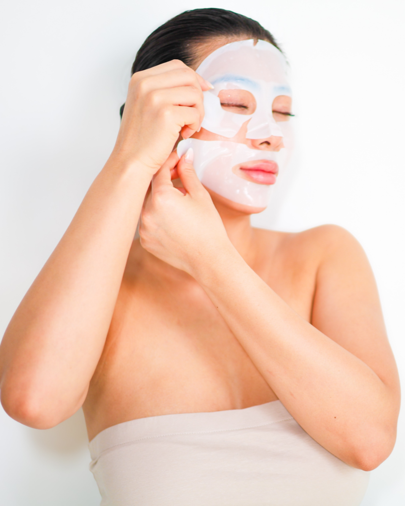 Woman applying collagen face mask against a white background